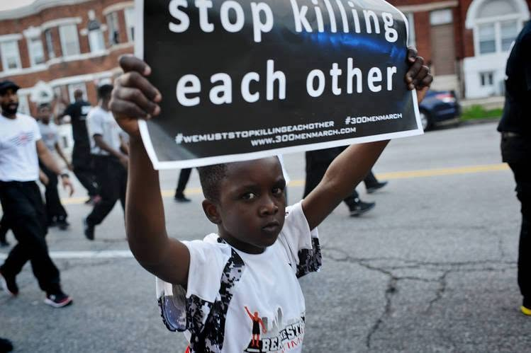 A young Black boy at a march holds a sign reading 'stop killing each other' with hashtag #300MenMarch
